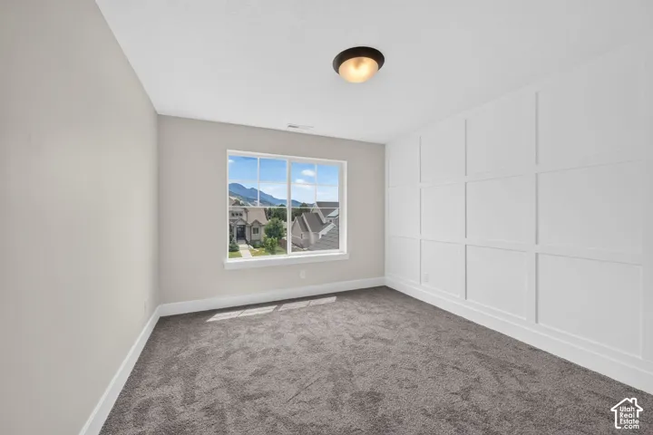 Room featuring an accent wall with wainscoting, white baseboards, and neutral wall paint