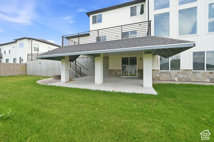Expansive green lawn with a covered patio featuring square columns and a sliding glass door entry