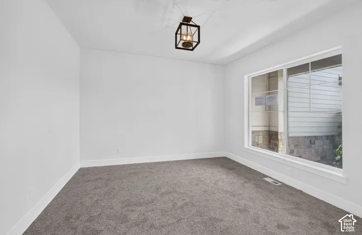 Bright room featuring white walls, gray carpet, a window with white trim, and a black metal lantern-style ceiling fixture