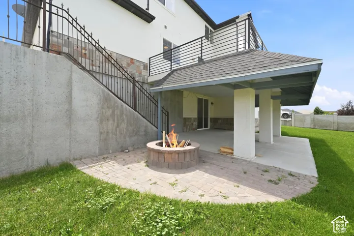 Covered patio area with a concrete slab and a built-in fire pit on a paver base