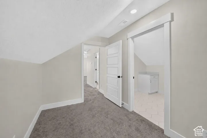 Carpeted hallway featuring an angled ceiling and recessed lighting