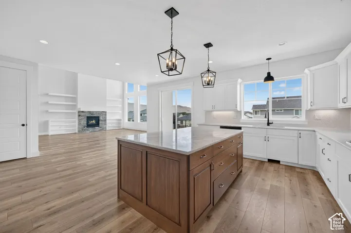Spacious open-concept living area featuring a large kitchen island with a stone countertop, white shaker cabinetry, and wood-finish flooring