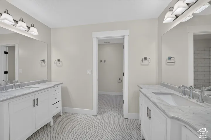 Dual white vanity with undermount sinks, stone countertops, and chrome fixtures