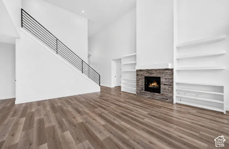 Spacious living area featuring high vaulted ceilings, wood-finish flooring, and a contemporary fireplace with a stone surround