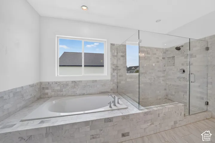 Walk-in shower with clear glass enclosure and built-in niche, featuring tile surround and dual-function shower head