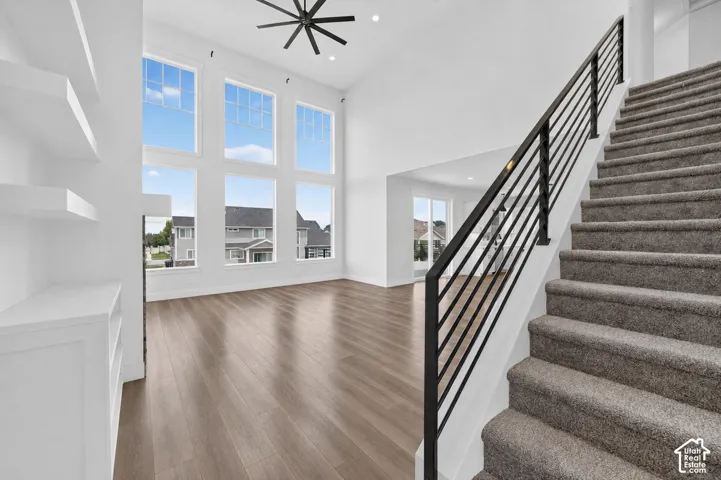 Bright living space featuring a two-story window wall, wood-finish flooring, and a contemporary ceiling fan