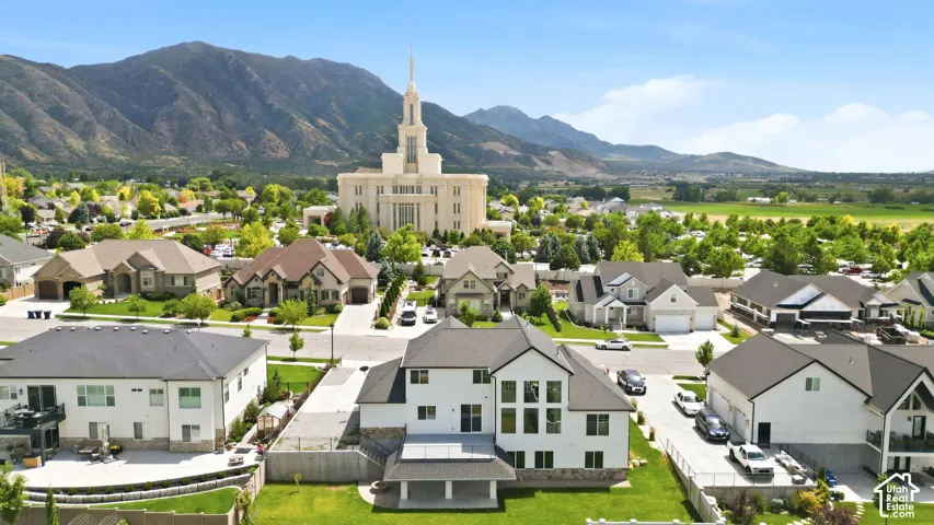Expansive residential area featuring a prominent white building with a spired roof, surrounded by mature trees and mountain ranges in the background