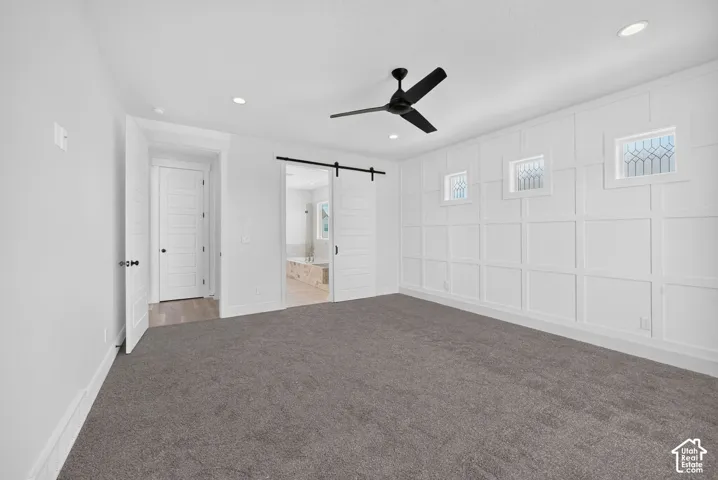 Spacious room featuring a decorative accent wall with three transom windows, a contemporary ceiling fan, recessed lighting, and soft grey carpeting
