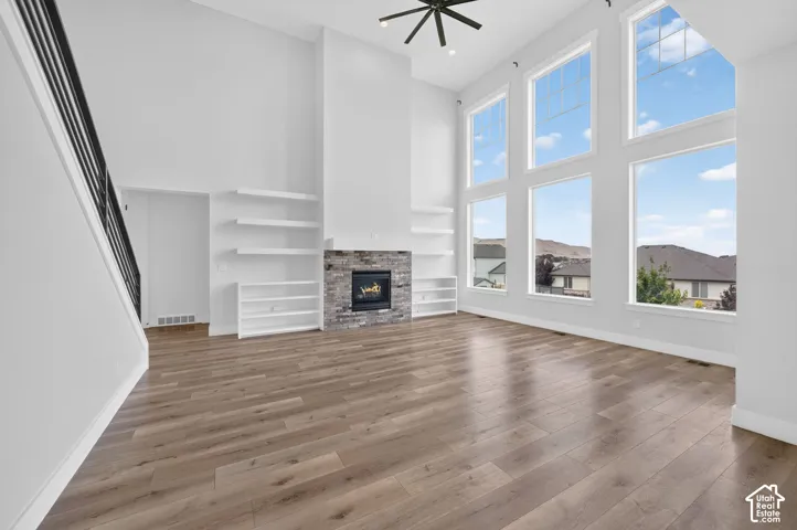Spacious living area featuring a dramatic two-story ceiling, a stone-clad fireplace, and extensive wood-finish flooring
