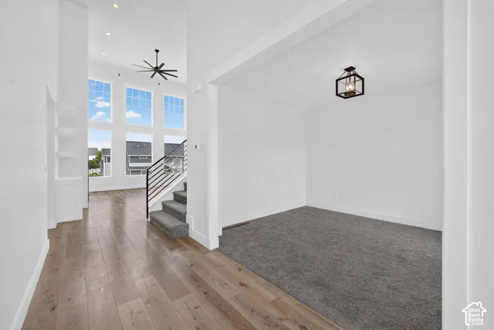 Two-story foyer featuring wood-finish flooring, a contemporary ceiling fan, and built-in shelving