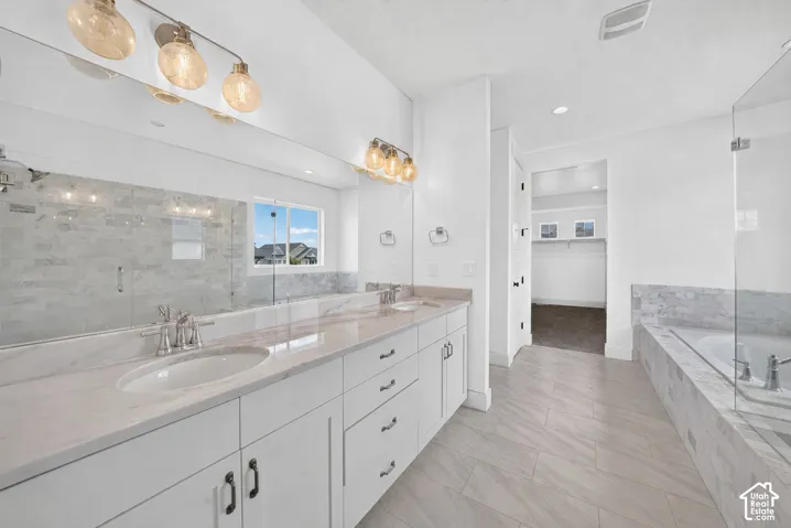 Dual vanity with white cabinetry and light-toned countertops, featuring a full-width mirror and contemporary lighting fixtures