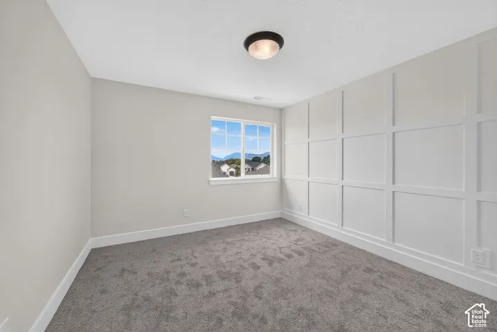 Interior room featuring a large picture window, board and batten accent wall, neutral wall paint, gray carpet flooring, and a flush mount ceiling light fixture