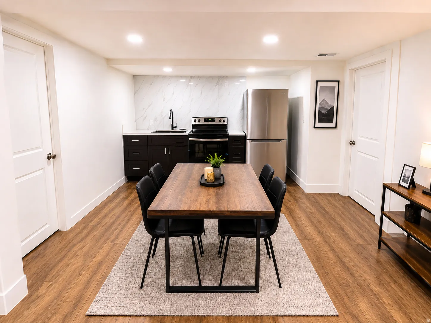 Open-concept kitchen and dining area featuring wood-finish flooring, recessed lighting, and white walls