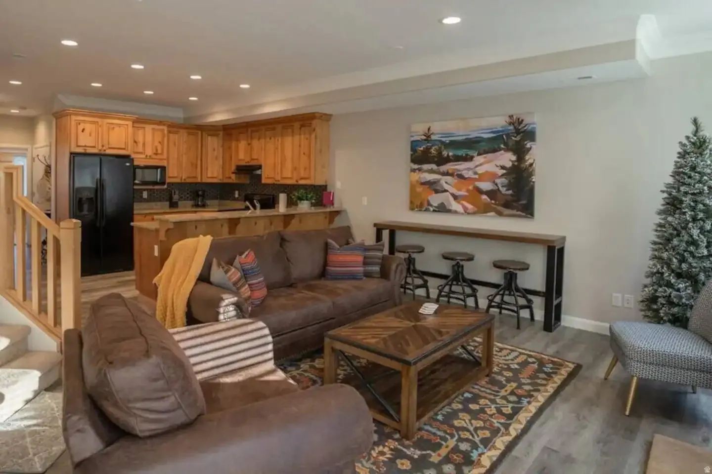 Open-concept living space featuring wood-finish flooring, recessed lighting, and a built-in kitchen with wood cabinetry and a breakfast bar