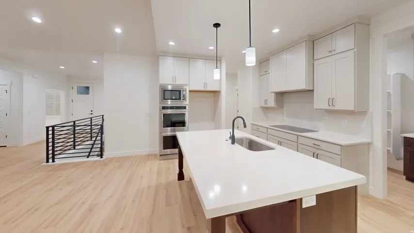 Modern kitchen featuring a large island with an undermount sink and pendant lighting