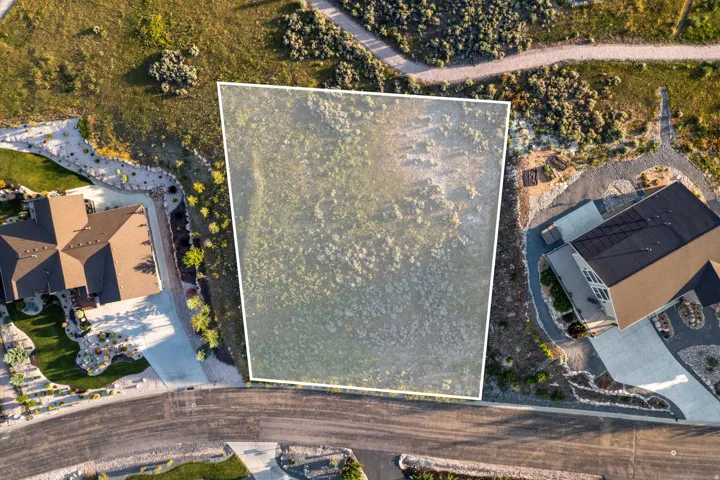 Expansive land parcel with surrounding residential properties, natural vegetation, and paved roads