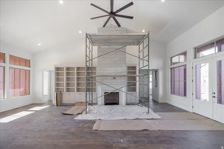 Vaulted ceiling with recessed lighting, exposed beam-style ceiling fan, and large fireplace with a tiled surround