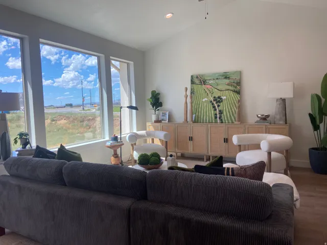 Spacious living area featuring large windows, vaulted ceilings, recessed lighting, wood-finish flooring, and a ceiling fan