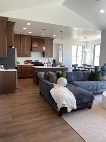Open-concept living space featuring wood-finish flooring, vaulted ceilings, and recessed lighting