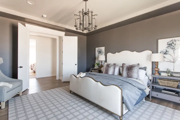 Spacious room featuring wood-finish flooring, a decorative ceiling light fixture, and a wide cased opening with double doors