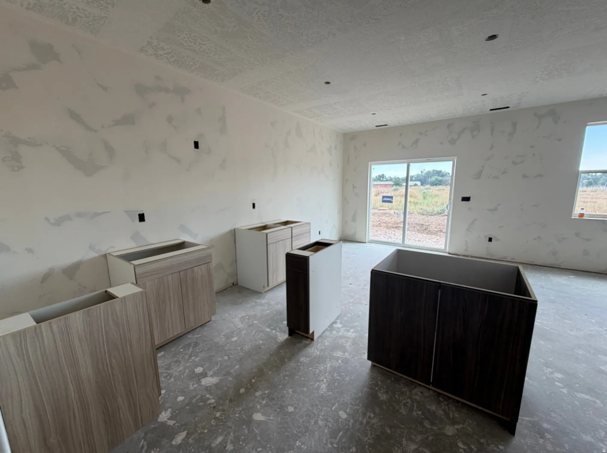 Open-concept space featuring multiple base cabinetry units, two windows, and a sliding glass door
