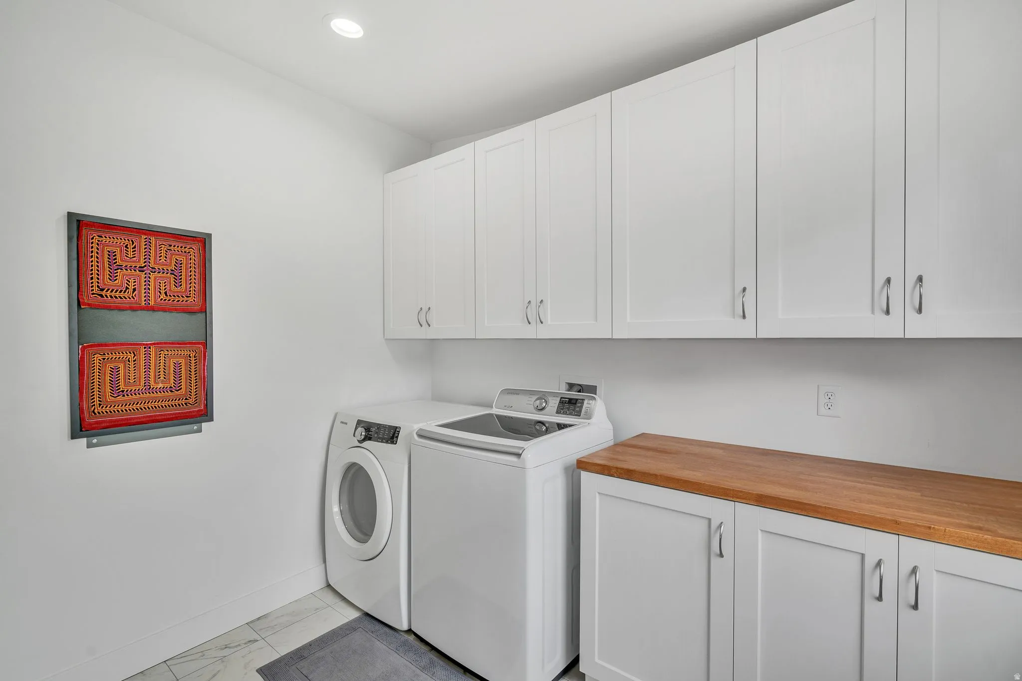 Laundry room featuring extensive white cabinetry, a wood-finish countertop, recessed lighting, and tile flooring