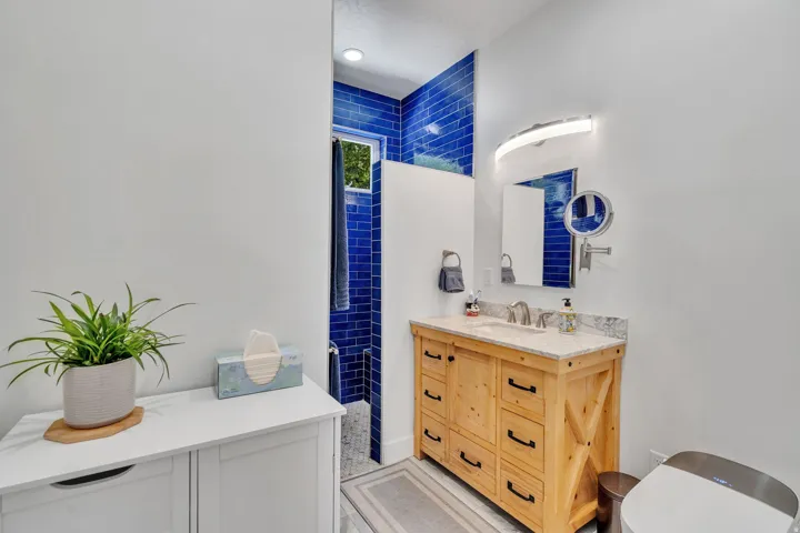 Bathroom featuring a wood vanity and  blue subway tile accents