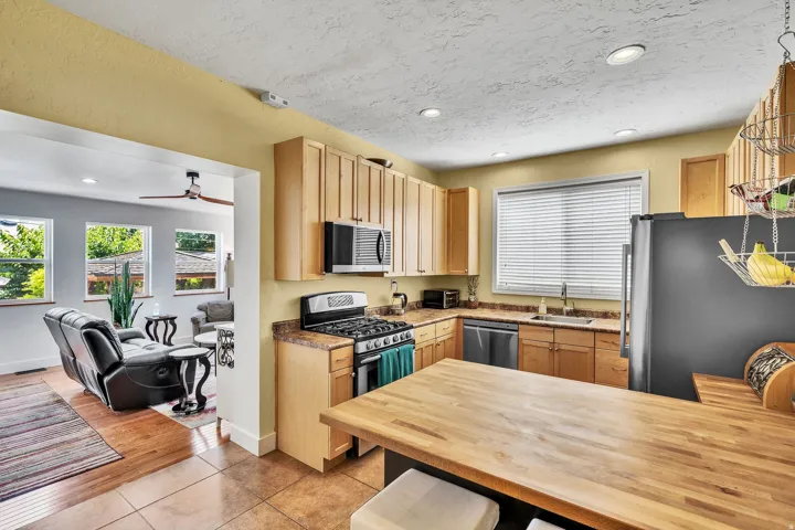 Kitchen featuring wood-finish cabinetry, stainless steel appliances, a gas range, and a wood-finish island countertop