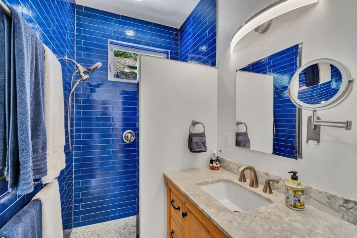 blue subway tile surround and a window, complemented by a vanity with a light-colored countertop