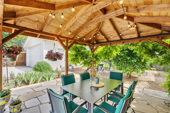 Expansive outdoor patio featuring a gazebo with built-in string lighting, flagstone patio and a landscaped garden