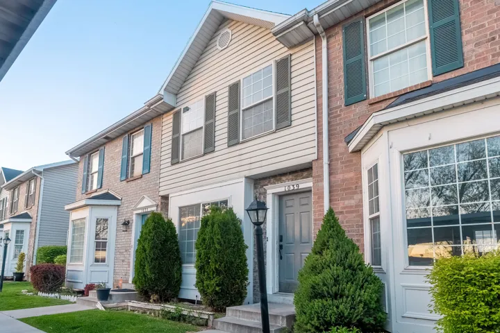 Brick and siding exterior featuring a bay window, decorative shutters, and a gray front door with an exterior lantern fixture
