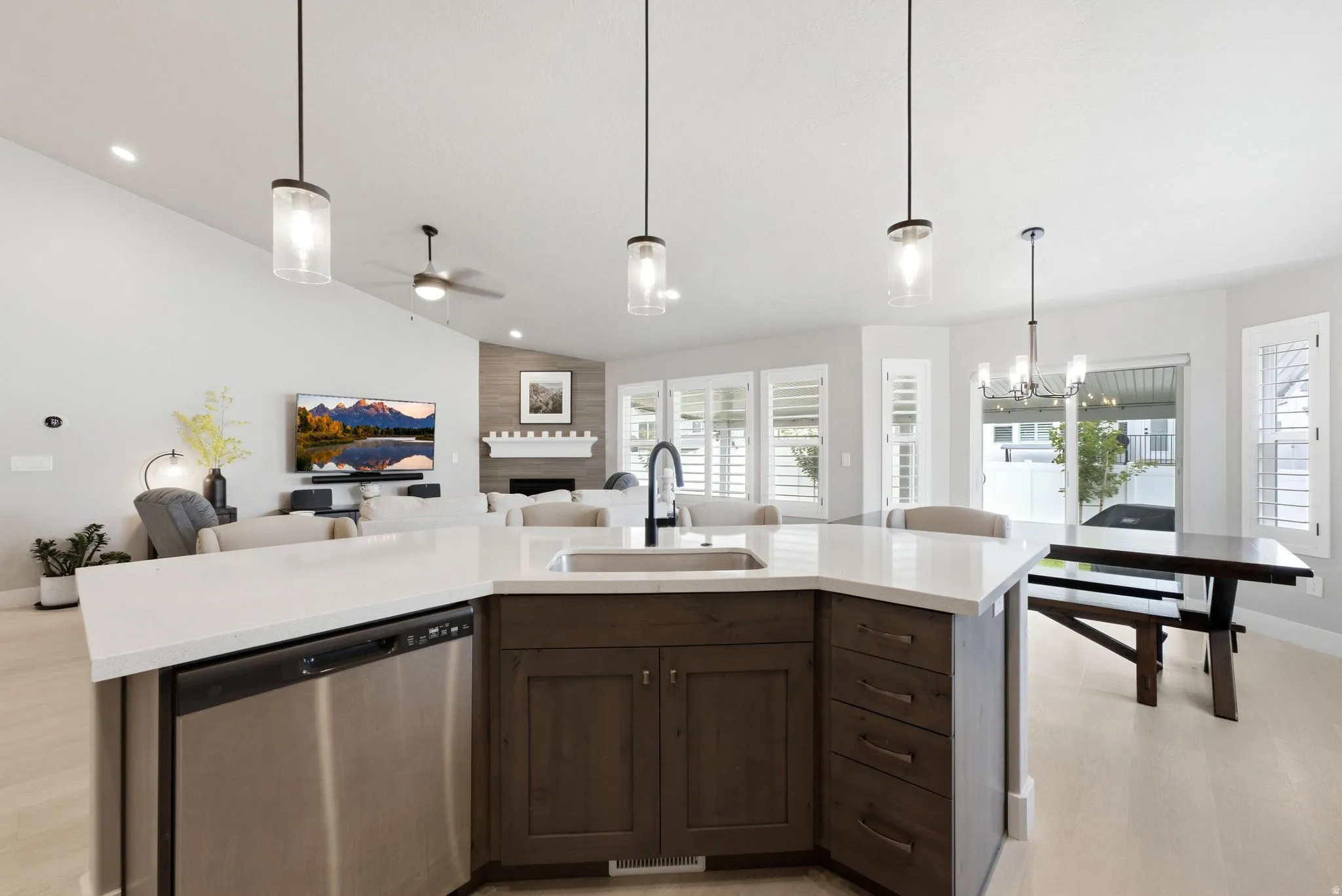 Open-concept living area featuring a kitchen island with quartz countertops, dark wood-finish cabinetry, and stainless steel appliances