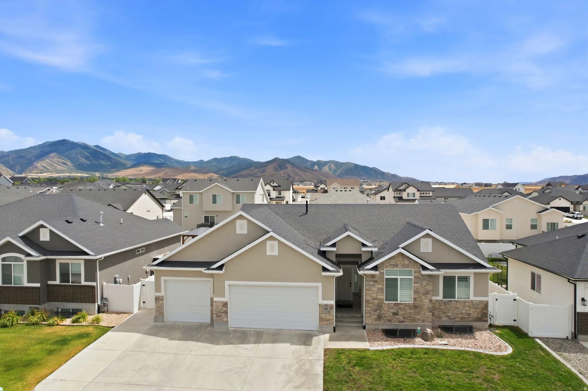Modern ranch-style home featuring a stone and stucco exterior, two-car garage, and established landscaping