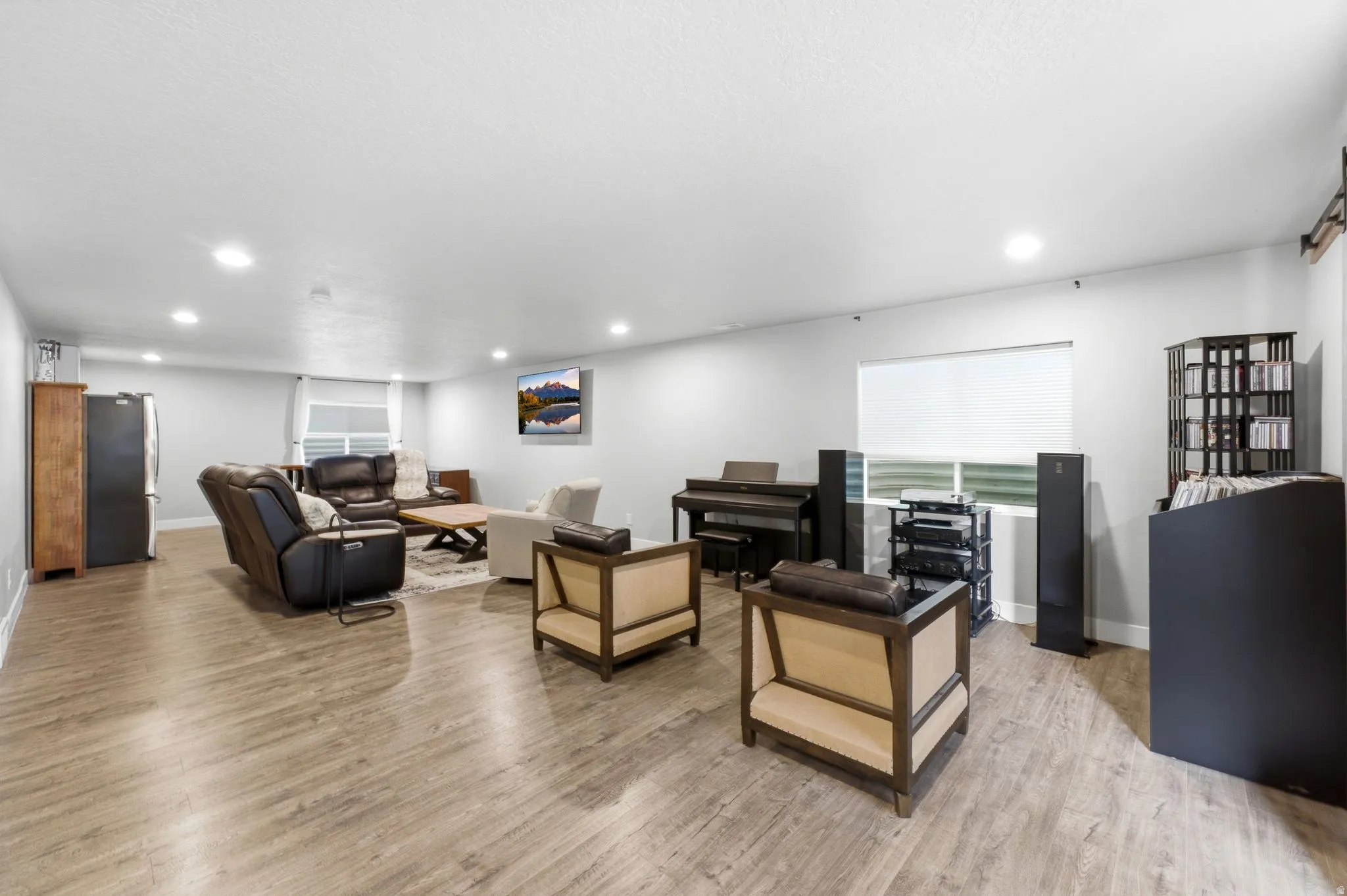 Spacious open-concept room featuring wood-finish flooring, recessed lighting, and light gray walls