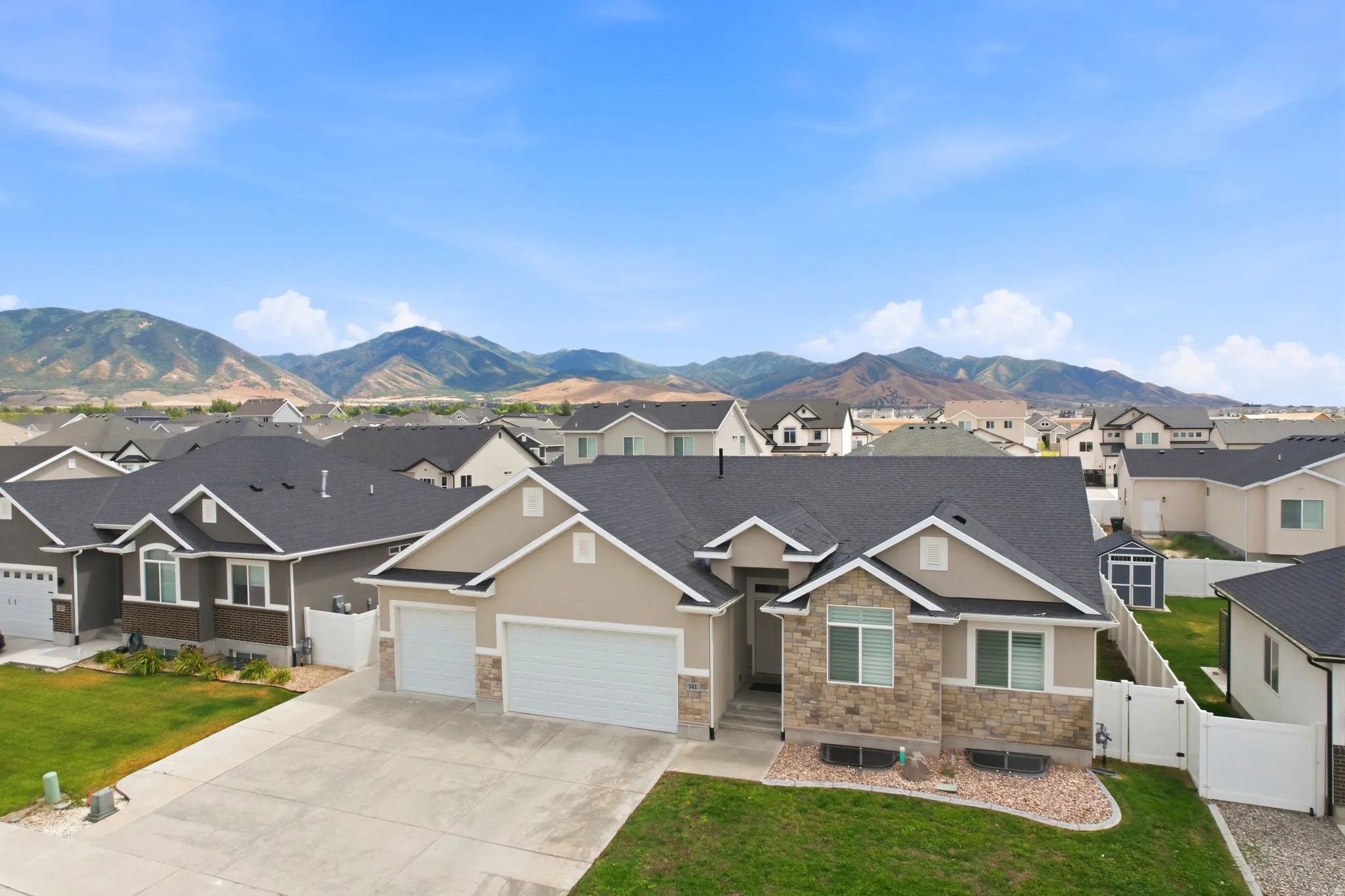 Single-story residence featuring a two-car garage, stone and stucco exterior, and a manicured front lawn