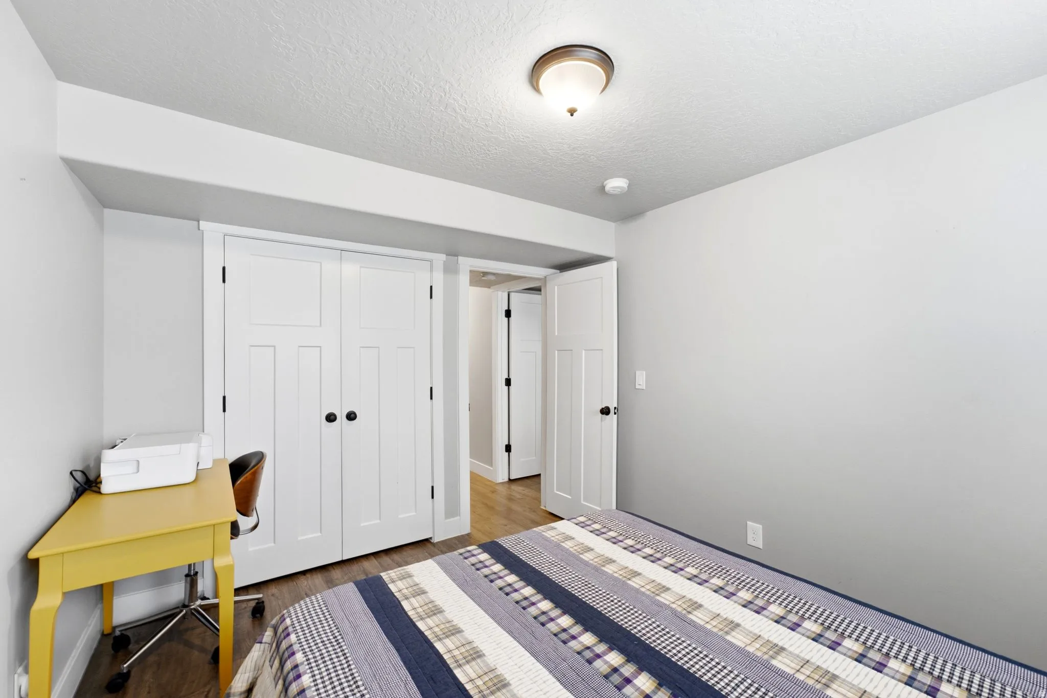 Interior room featuring wood-finish flooring, white paneled doors, and a flush mount ceiling light fixture