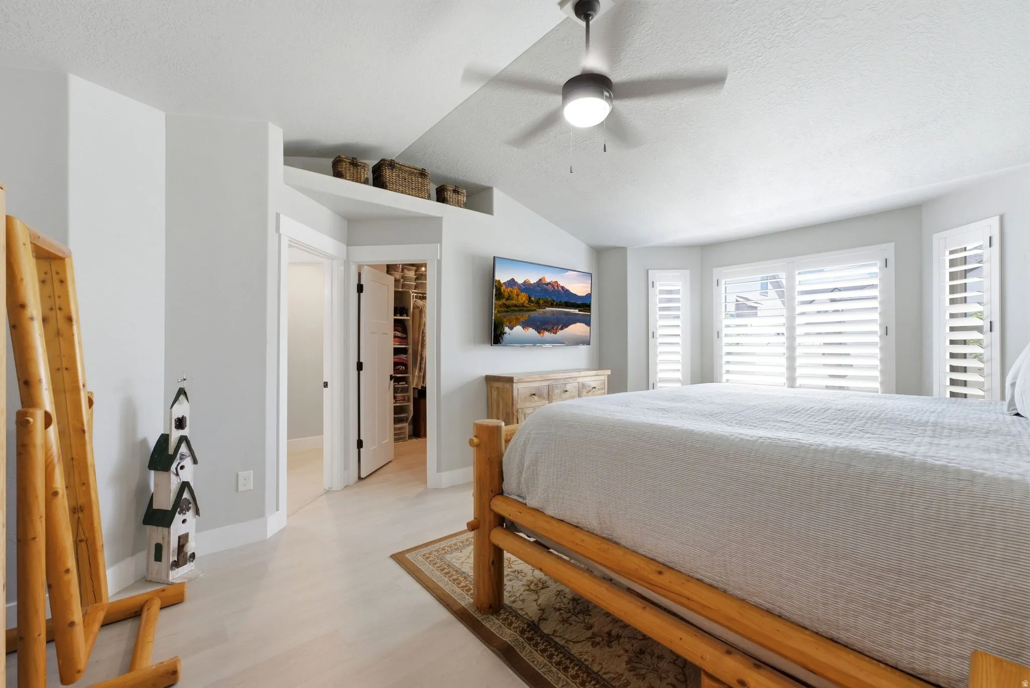 Spacious interior featuring light wood-finish flooring, vaulted ceilings, and a ceiling fan