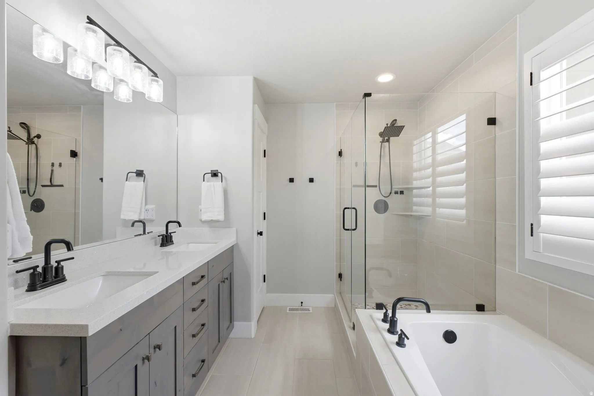 Double vanity with white countertops, matte black faucets, and gray wood-finish cabinetry