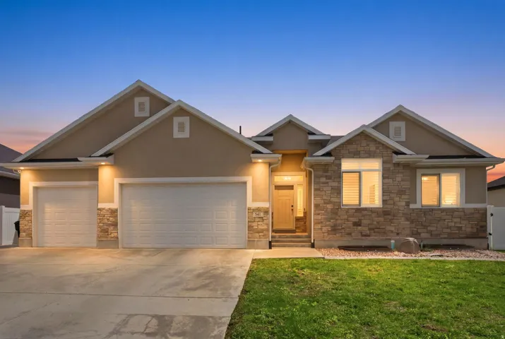 Contemporary stucco and stone exterior featuring multiple gables, a three-car garage, and a concrete driveway