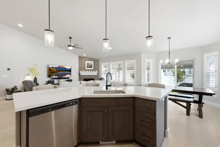 Open-concept living area featuring a kitchen island with quartz countertops, dark wood-finish cabinetry, and stainless steel appliances