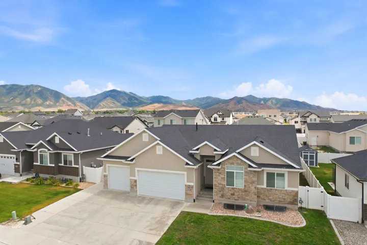 Single-story residence featuring a two-car garage, stone and stucco exterior, and a manicured front lawn