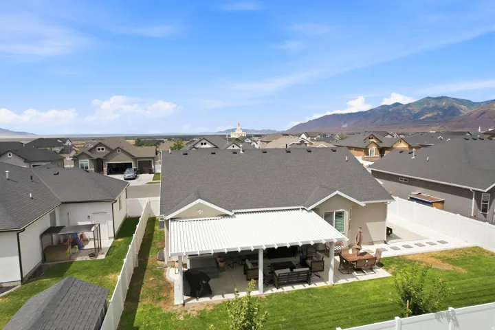 Expansive backyard featuring a covered patio, concrete hardscaping, green lawn, and full perimeter fencing