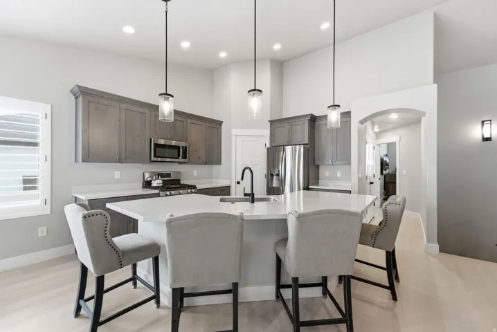Kitchen featuring a central island with countertop seating, stainless steel appliances, grey shaker-style cabinetry, light wood-finish flooring, and recessed lighting