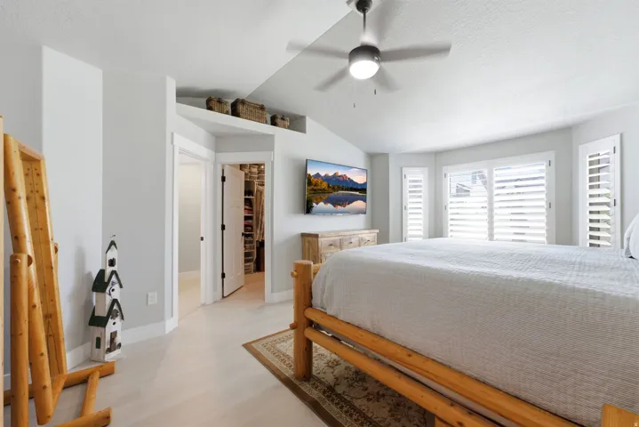 Spacious interior featuring light wood-finish flooring, vaulted ceilings, and a ceiling fan
