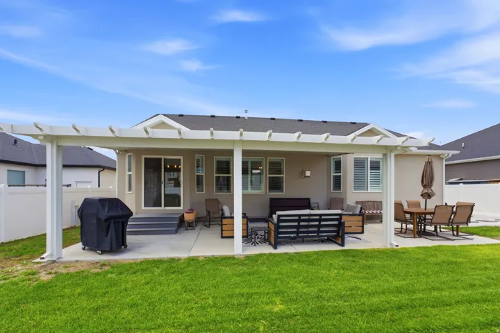 Rear exterior featuring a covered patio, concrete slab, sliding glass door access, and a green lawn