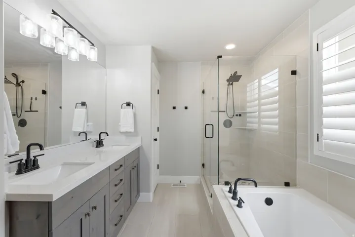 Double vanity with white countertops, matte black faucets, and gray wood-finish cabinetry