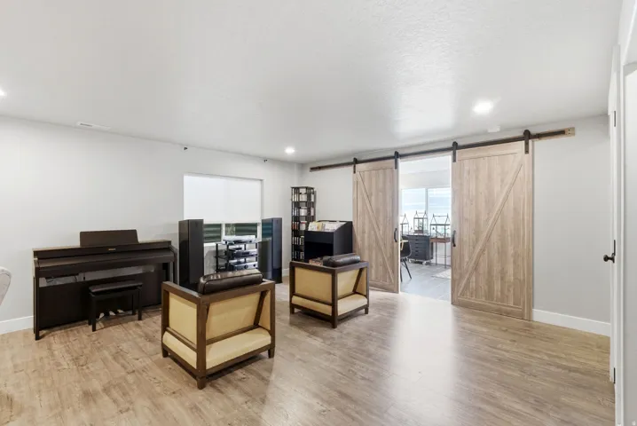 Spacious room featuring wood-finish flooring and recessed lighting