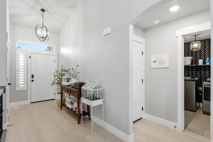 Inviting entryway featuring light wood-finish flooring, a vaulted ceiling, and an ornate globe pendant light