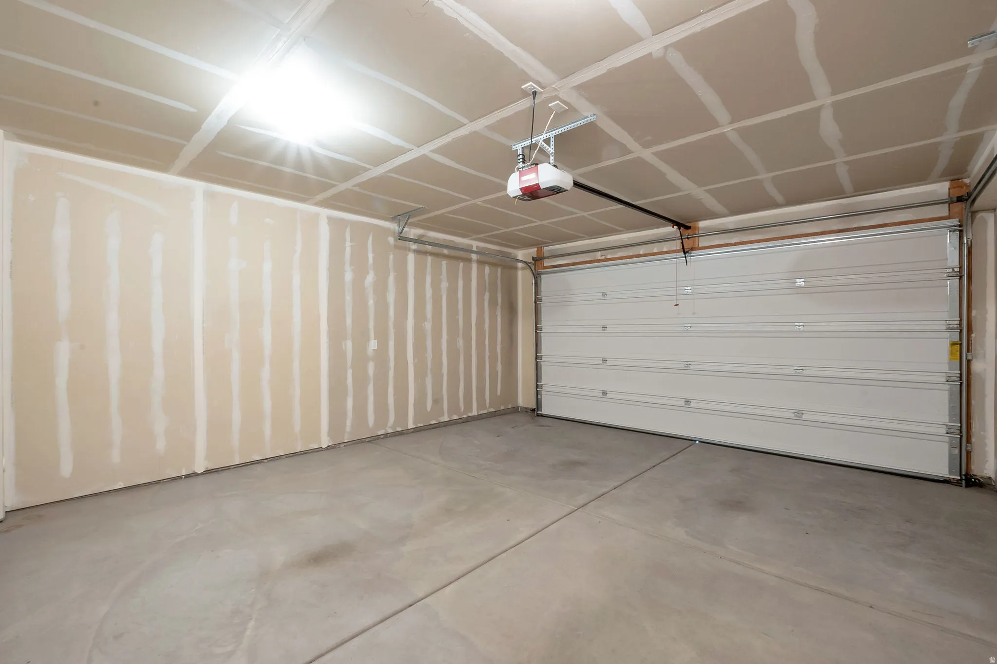 Spacious garage with a concrete floor, overhead lighting, and an automatic garage door opener