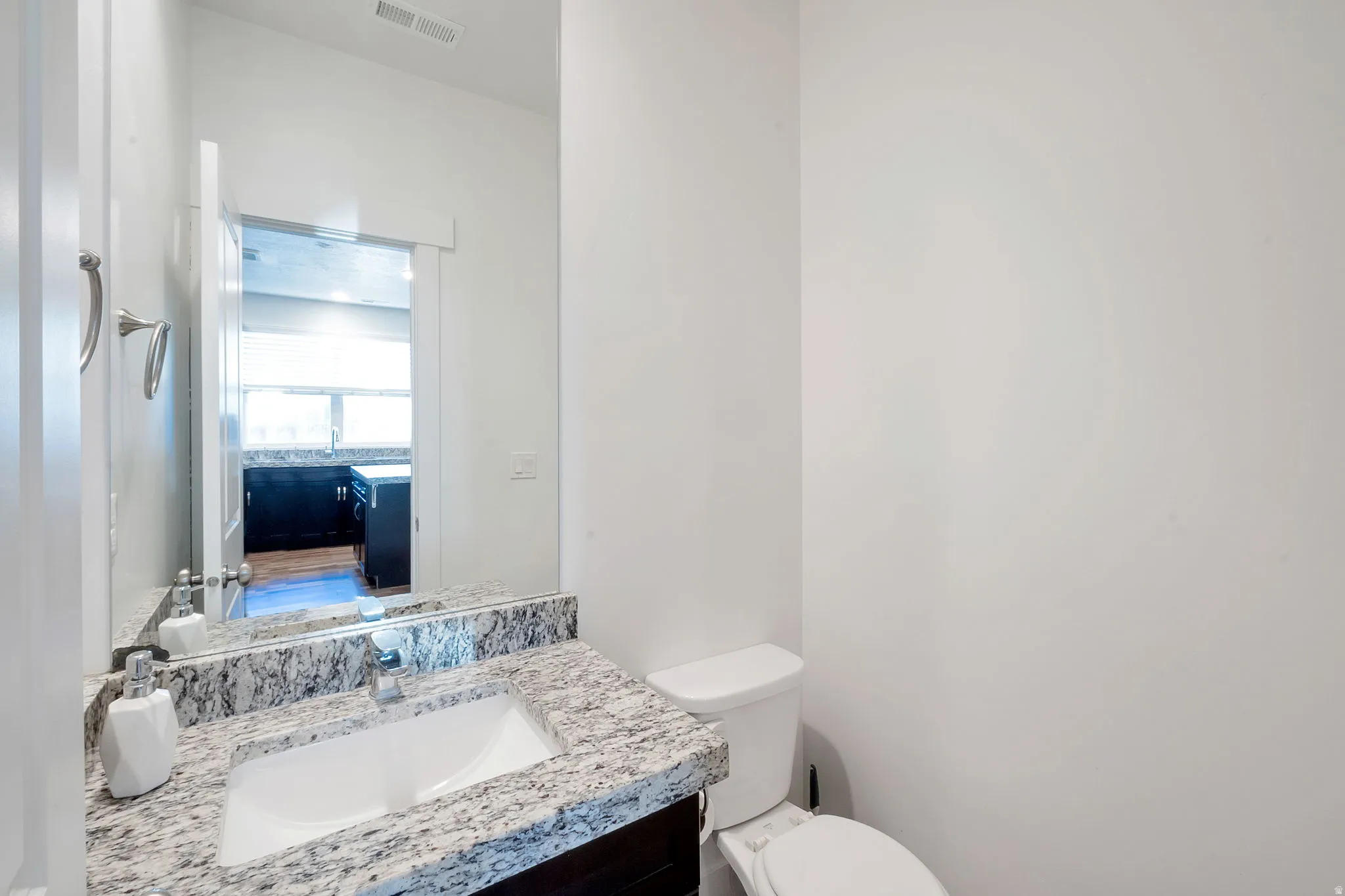 Vanity with stone countertop, undermount sink, and chrome faucet